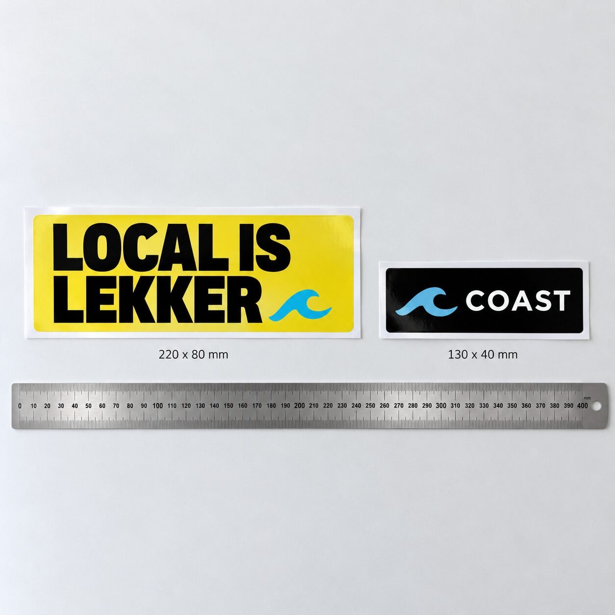220 x 80 mm and 130 x 40 mm bumper stickers side by side above a steel ruler